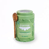 A mint green tea tin with a wooden scoop along the side of it sits on a white background.