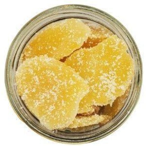 White background with a glass jar filled with Candied Ginger Slices with Cane Sugar.