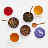 Three loose leaf teas and corresponding brewed teas with a hand carved wooden scoop. 