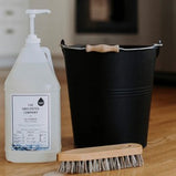 Unscented Co. All Purpose Cleaner, a black bucket and a wooden cleaning brush.