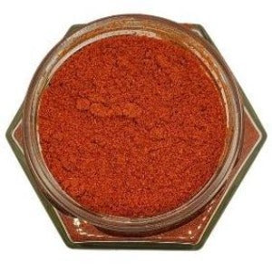 White background with a glass jar filled with Ground Cayenne Pepper.