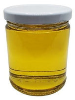A glass jar containing Organic Golden Jojoba Oil reflects a warm, amber radiance. The liquid, with a pure golden hue, exudes natural richness and vitality. The oil appears smooth and luxurious, promising nourishment and versatility. In the light, it glistens, showcasing its organic essence, inviting a tactile and visual experience of its natural brilliance and inherent beauty.