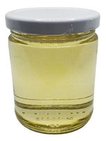 White background with a clear, glass jar filled with Avocado Oil sealed with a white lid.